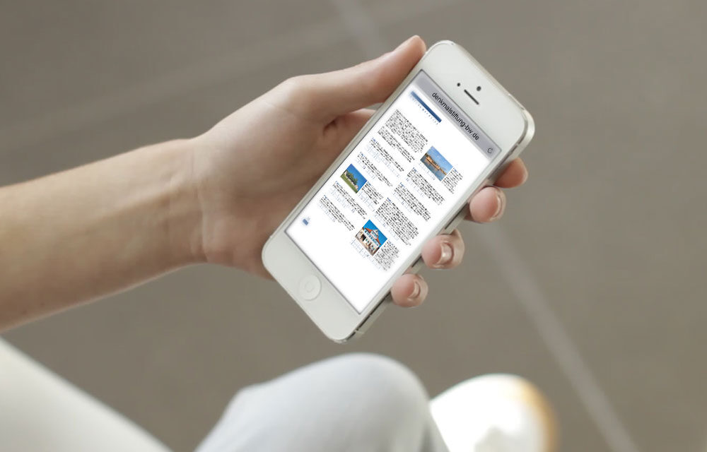 Eine Hand hält ein Mobiltelefon mit der Anzeige des Denkmalrätsels